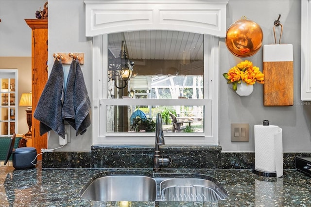 interior space featuring dark stone countertops, sink, and white cabinets