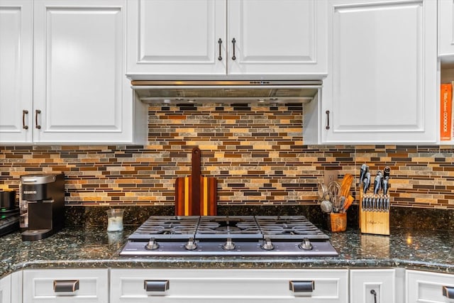 kitchen featuring decorative backsplash, dark stone counters, ventilation hood, white cabinetry, and stainless steel gas stovetop