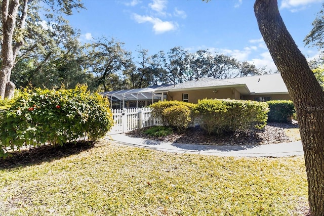 view of side of property with a lanai and a lawn