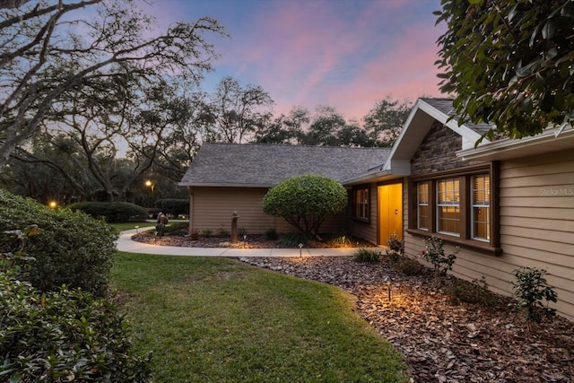 property exterior at dusk with a lawn