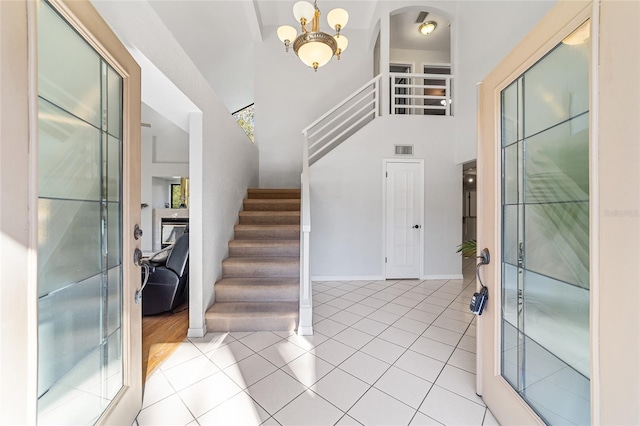 entryway featuring a towering ceiling, light tile patterned floors, and an inviting chandelier