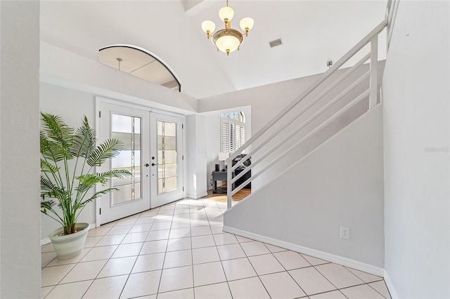 foyer entrance featuring french doors, light tile patterned floors, lofted ceiling, and a notable chandelier