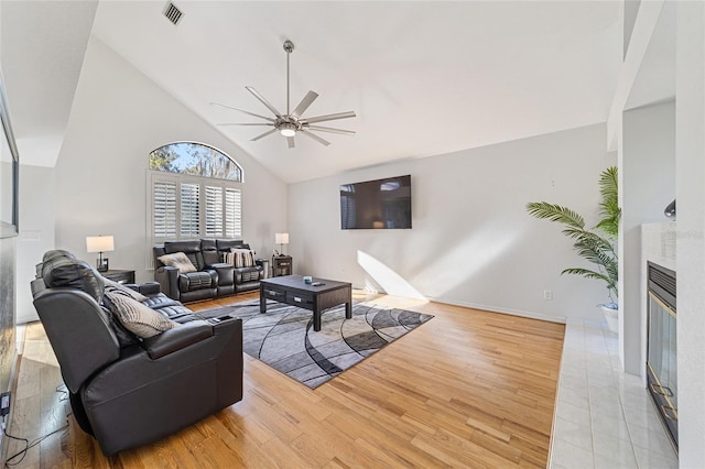 living room with ceiling fan, high vaulted ceiling, and light hardwood / wood-style floors