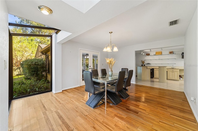 dining area featuring light hardwood / wood-style flooring, expansive windows, french doors, and a notable chandelier