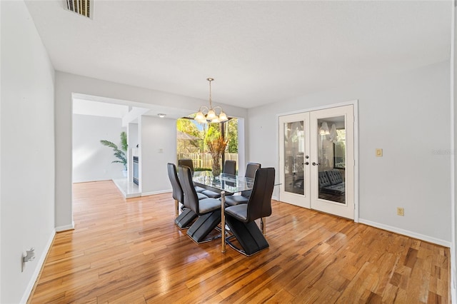 dining space featuring french doors, light hardwood / wood-style floors, and a notable chandelier