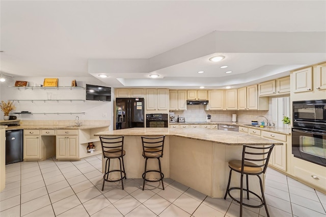 kitchen with black appliances, sink, light stone countertops, a kitchen island, and a kitchen bar