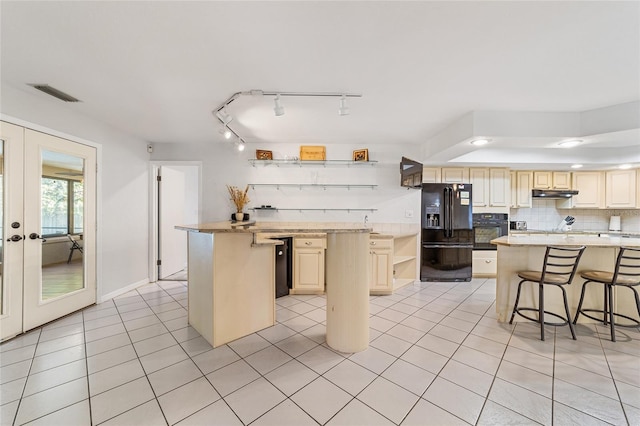 kitchen with a kitchen bar, french doors, black appliances, light tile patterned floors, and a kitchen island