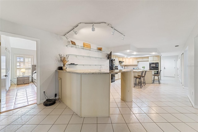 kitchen with rail lighting, a kitchen breakfast bar, kitchen peninsula, light tile patterned floors, and black appliances