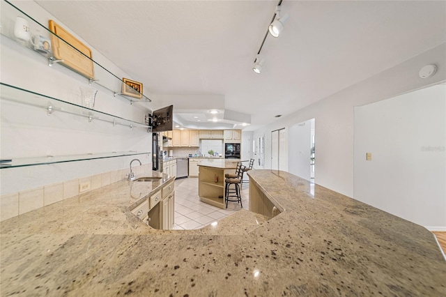 kitchen featuring dishwasher, sink, light stone counters, a breakfast bar area, and a kitchen island