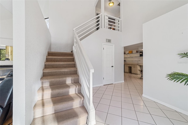 stairs with tile patterned flooring and a high ceiling