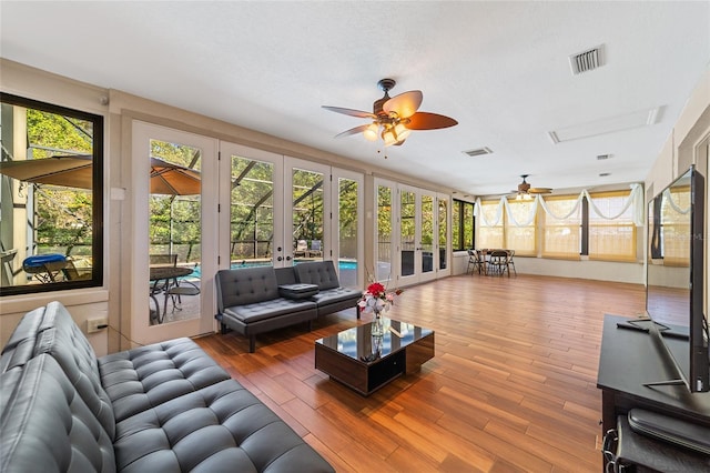 living room featuring ceiling fan, french doors, hardwood / wood-style floors, and a textured ceiling