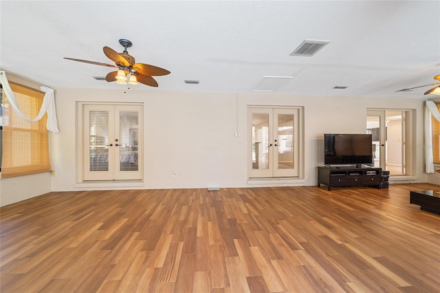 unfurnished living room featuring ceiling fan, french doors, and hardwood / wood-style floors