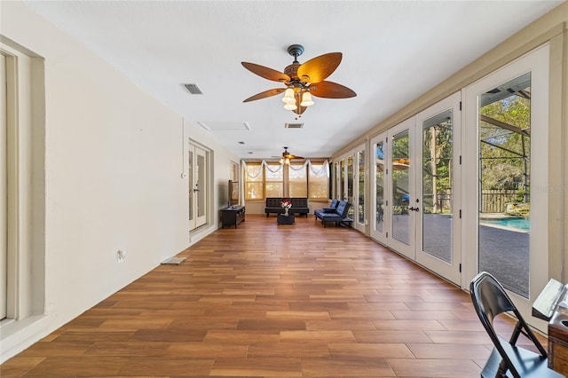 unfurnished sunroom featuring ceiling fan and french doors