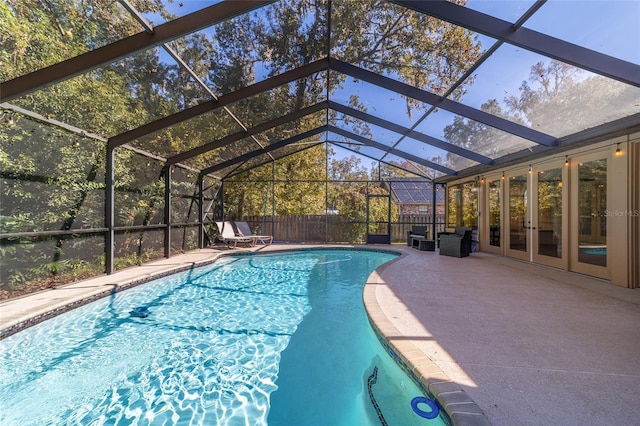 view of pool featuring glass enclosure, french doors, and a patio