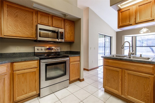 kitchen featuring light tile patterned floors, stainless steel appliances, lofted ceiling, and sink