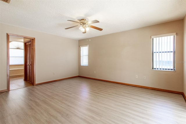 spare room featuring ceiling fan, a healthy amount of sunlight, a textured ceiling, and light hardwood / wood-style flooring