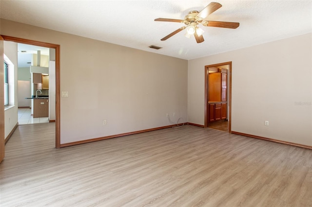 empty room featuring ceiling fan, light hardwood / wood-style floors, sink, and a textured ceiling