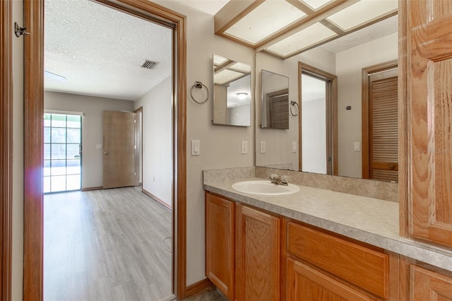 bathroom featuring vanity, wood-type flooring, and a textured ceiling