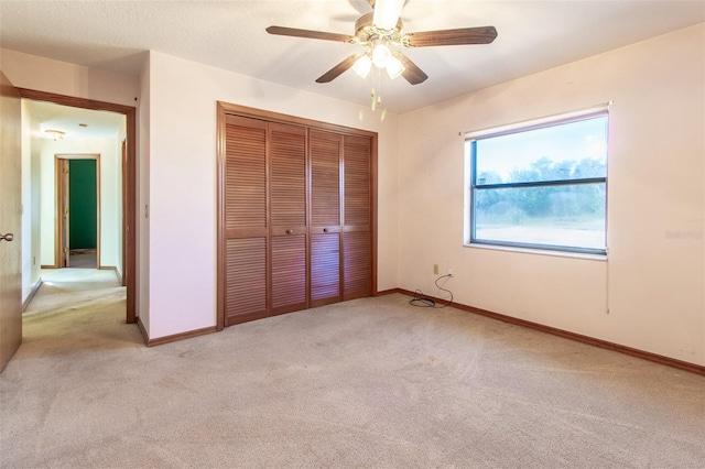 unfurnished bedroom featuring light carpet, a closet, and ceiling fan