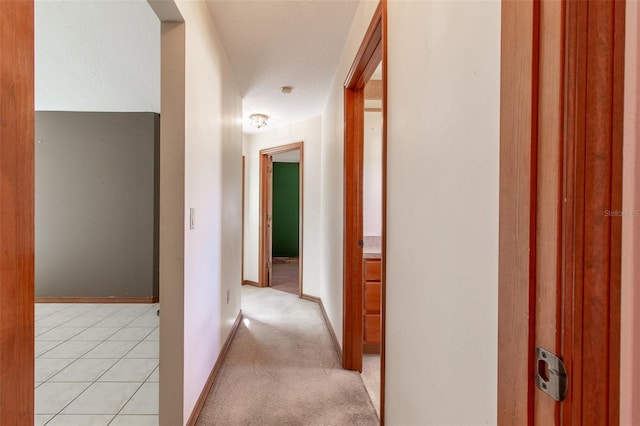 hallway with light colored carpet and a textured ceiling