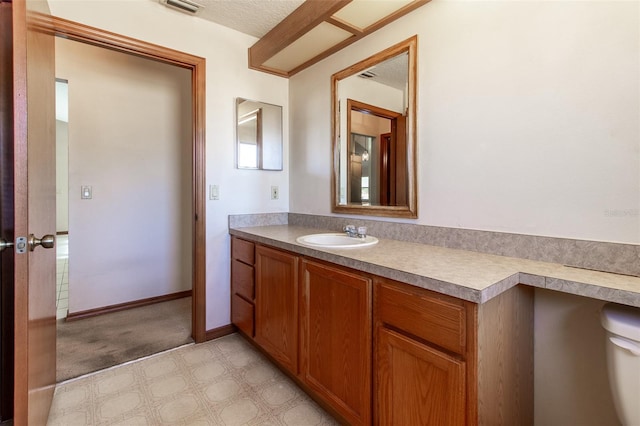 bathroom featuring vanity, toilet, and a textured ceiling