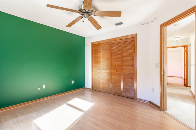 unfurnished bedroom featuring ceiling fan, a closet, and light hardwood / wood-style flooring