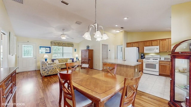 dining space with ceiling fan with notable chandelier, light wood-type flooring, and lofted ceiling