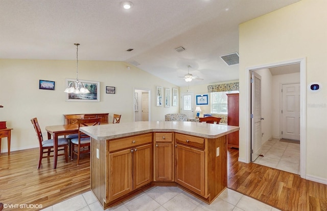 kitchen featuring a center island, hanging light fixtures, light hardwood / wood-style floors, lofted ceiling, and ceiling fan with notable chandelier