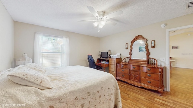 bedroom with a textured ceiling, light hardwood / wood-style flooring, and ceiling fan