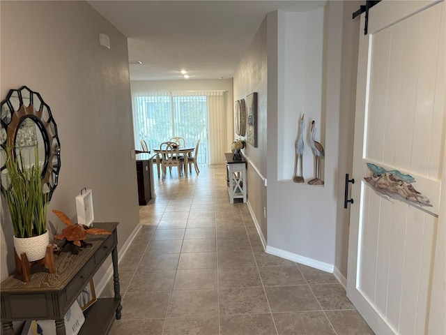 corridor featuring a barn door and tile patterned floors