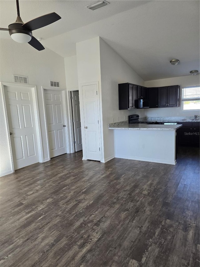 kitchen with dark hardwood / wood-style flooring, kitchen peninsula, light stone counters, and electric stove