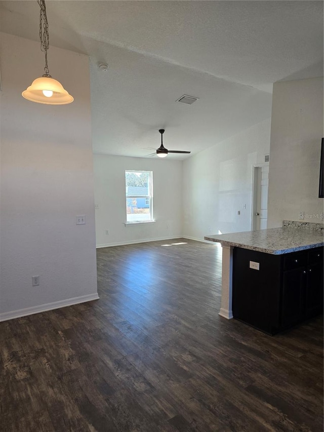 kitchen featuring light stone counters, pendant lighting, ceiling fan, and dark hardwood / wood-style flooring