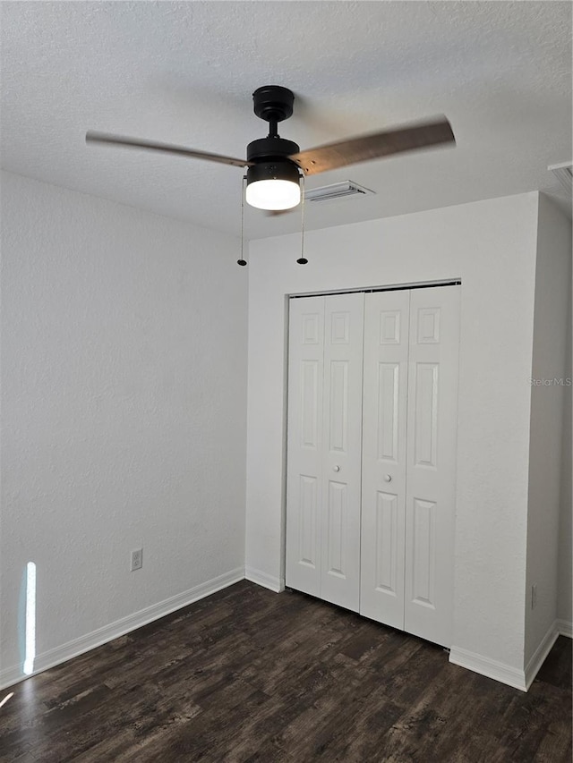 unfurnished bedroom with a textured ceiling, a closet, ceiling fan, and dark hardwood / wood-style flooring