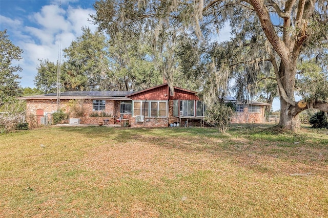 rear view of house with a sunroom, a yard, and solar panels