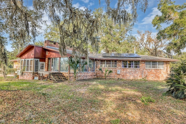 rear view of house with a sunroom and solar panels