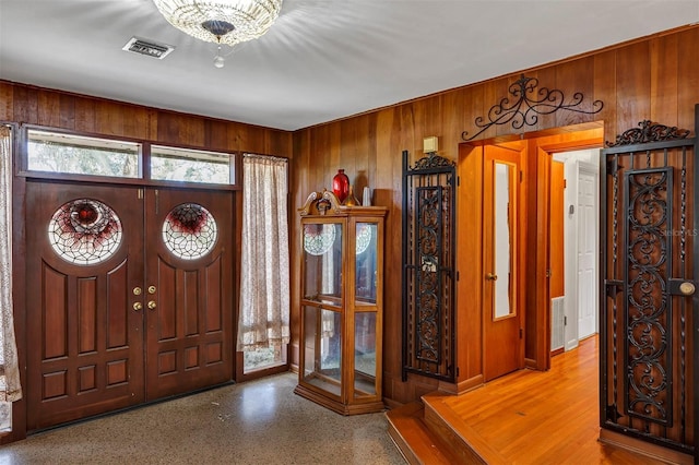 entrance foyer with a chandelier and wood walls