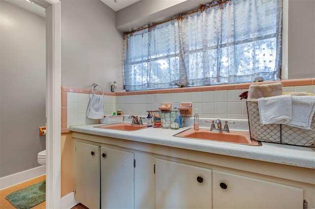 bathroom featuring vanity, toilet, and backsplash