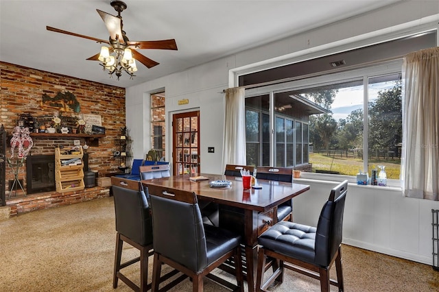 dining space featuring ceiling fan and a brick fireplace