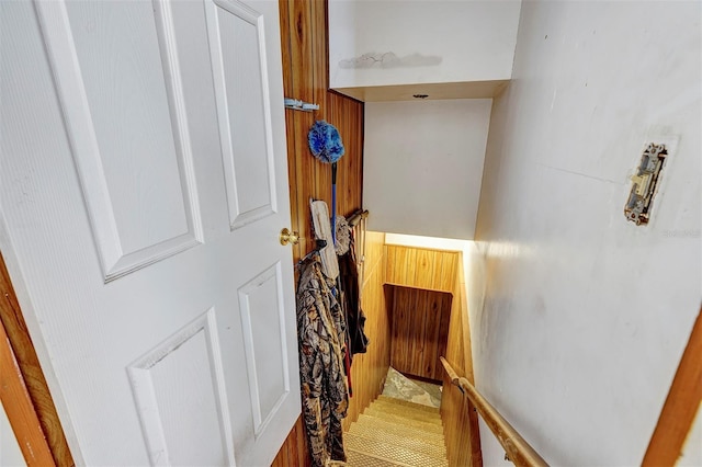 stairway featuring wooden walls