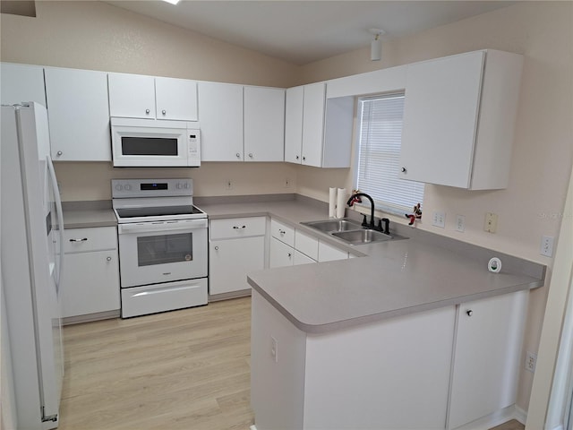 kitchen with white appliances, white cabinets, sink, light hardwood / wood-style floors, and kitchen peninsula