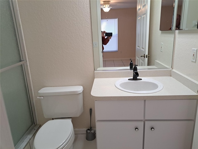 bathroom featuring ceiling fan, vanity, a shower with shower door, and toilet