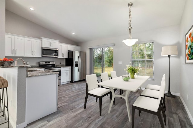 dining space featuring sink, dark wood-type flooring, and vaulted ceiling