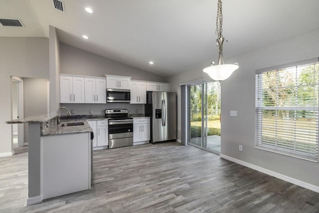 kitchen featuring stainless steel appliances, vaulted ceiling, sink, pendant lighting, and white cabinetry