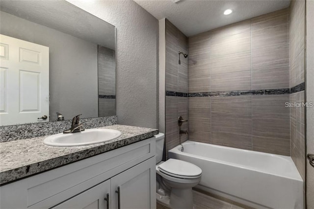 full bathroom with tiled shower / bath combo, toilet, a textured ceiling, and vanity