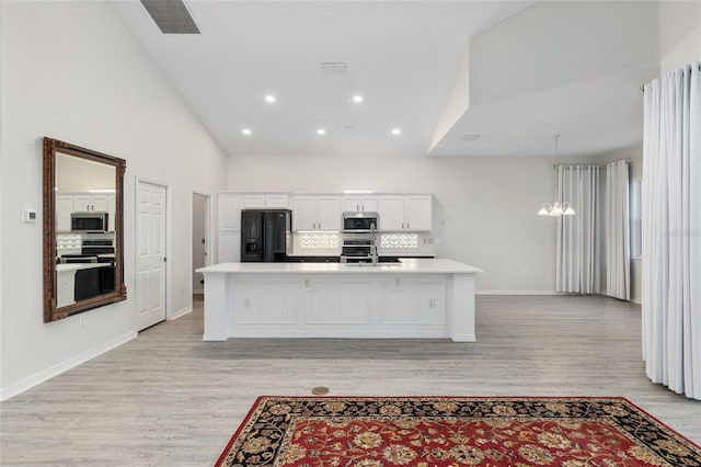 kitchen featuring a spacious island, backsplash, appliances with stainless steel finishes, and light hardwood / wood-style flooring