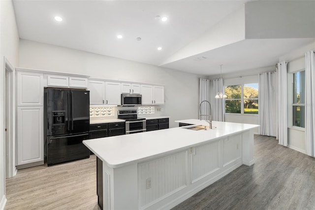 kitchen featuring a kitchen island with sink, white cabinets, stainless steel appliances, and vaulted ceiling