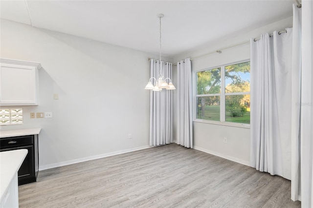 unfurnished dining area with a chandelier and light hardwood / wood-style flooring