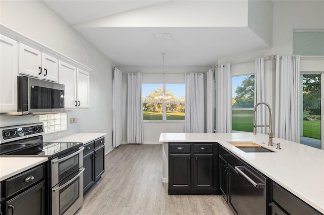 kitchen with appliances with stainless steel finishes, white cabinetry, a healthy amount of sunlight, and sink