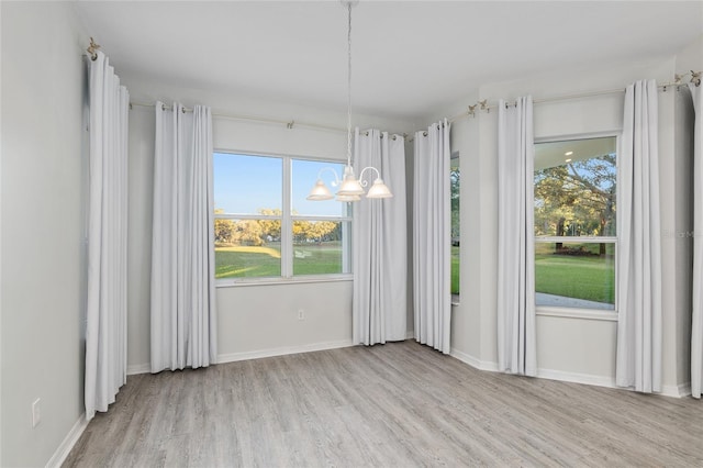 unfurnished dining area featuring light hardwood / wood-style floors and an inviting chandelier