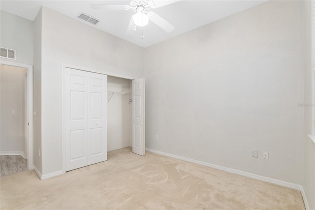 unfurnished bedroom featuring ceiling fan, light carpet, and a closet